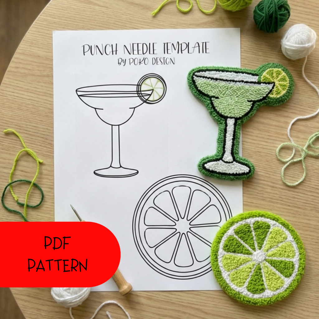 Summer-themed punch needle art of a refreshing margarita cocktail and a sliced lime, surrounded by green yarn balls on a wooden workspace.