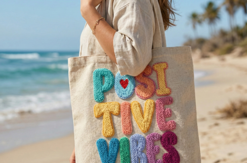 "Positivity Vibes" punch needle design featuring abstract floral elements embroidered on a linen canvas bag in dusty rose and cream